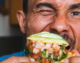 Homme mangeant un tacos aux crevettes